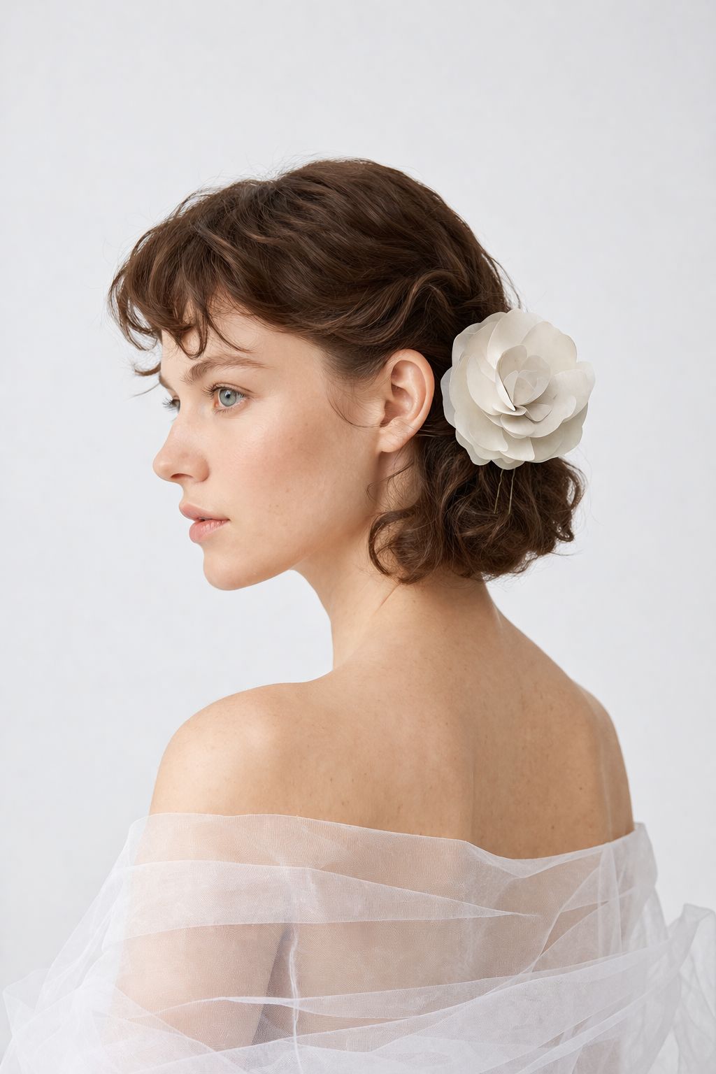 Woman with a white floral hair accessory against a plain background