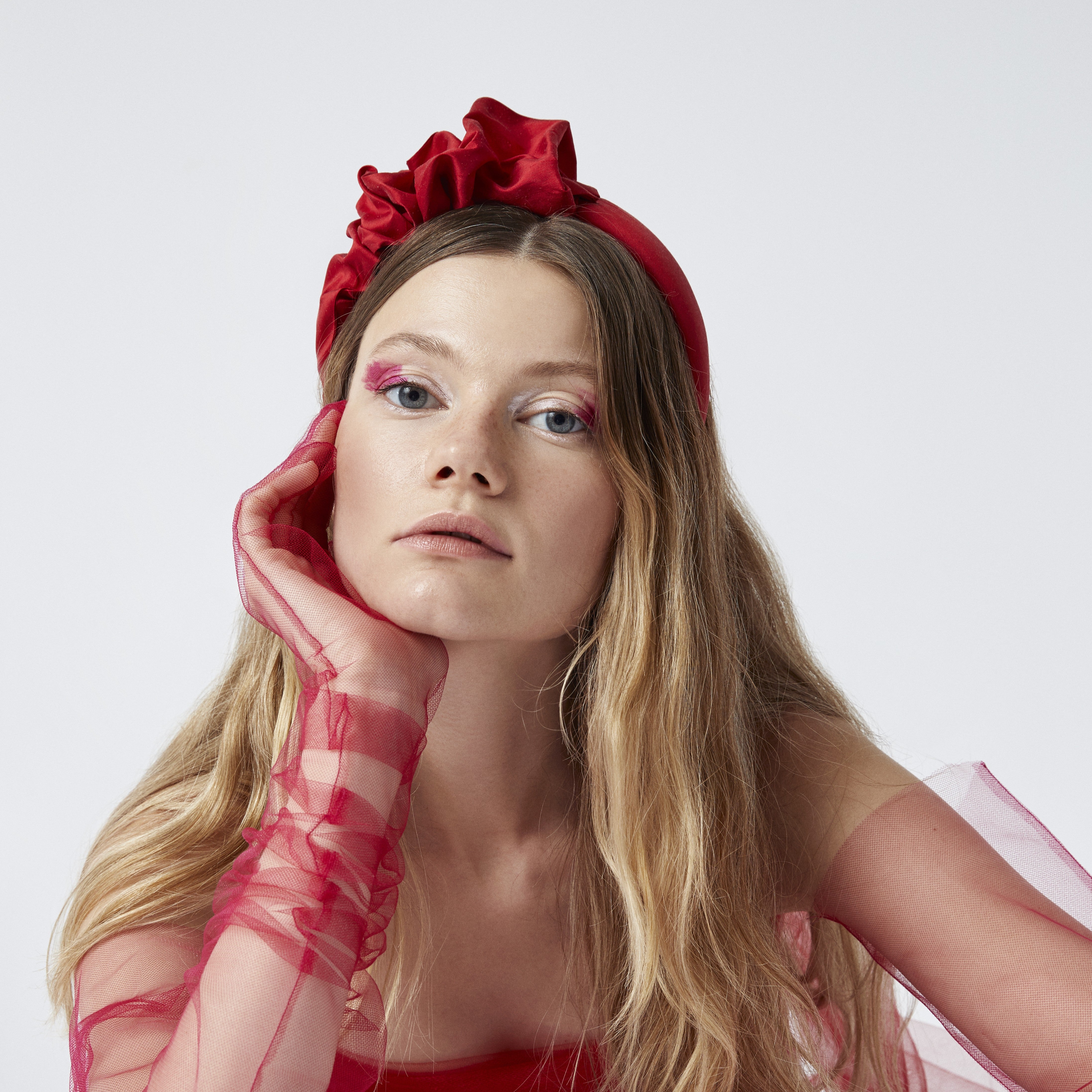 Woman wearing a red headband and gloves against a white background
